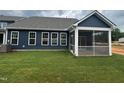 Home featuring a screened-in porch and dark blue siding, surrounded by a lush, newly installed lawn at 771 Old Station Pointe, Angier, NC 27501