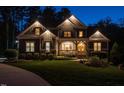 A charming house with illuminated windows and landscape lighting at dusk at 107 Bella Casa Way, Clayton, NC 27527