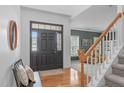 Bright foyer featuring hardwood floors, staircase, front door with sidelights, and a glimpse into the living room at 120 Wellspring Dr, Holly Springs, NC 27540
