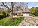 Beautiful home showcasing a manicured front lawn, long driveway and mature shade tree in a suburban neighborhood at 1204 Croydon Glen Ct, Cary, NC 27519