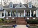 Inviting front porch with classic columns and brick accents that leads up to the main entrance at 1229 Westerham Dr, Wake Forest, NC 27587