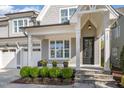 A charming covered front porch with stone steps, decorative flower pots, a black front door, and gray siding at 142 Old Piedmont Cir, Chapel Hill, NC 27516