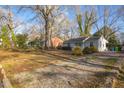 Exterior shot of a compact home with a gravel driveway and budding foliage at 2457 Derby Dr, Raleigh, NC 27610