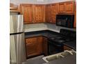 Well-maintained kitchen featuring wood cabinets, black appliances, and sleek countertops in a cozy layout at 2631 Oldgate Dr # 101, Raleigh, NC 27604