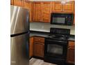 Close-up of a kitchen with stainless steel refrigerator, range, microwave, and dark countertop at 2631 Oldgate Dr # 101, Raleigh, NC 27604