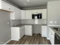 Modern kitchen featuring white cabinets, stainless steel microwave, and tile backsplash at 279 Constellation Ct, Benson, NC 27504