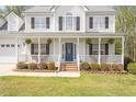 Inviting covered front porch with white railing, hanging plants, and a decorative front door at 53 Stafford Cir, Clayton, NC 27527