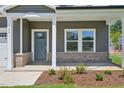 An inviting covered front porch featuring brick accents, a modern door, and manicured landscaping at 700 Deschutes Dr, Garner, NC 27529
