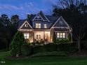 Beautiful home with a mix of stone and siding illuminated at dusk, showcasing manicured landscaping at 7312 Ridgeline Dr, Raleigh, NC 27613