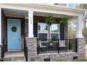 Inviting front porch with stone detail, hanging ferns, and cozy seating area offering curb appeal at 104 Chaseford Ct, Holly Springs, NC 27540