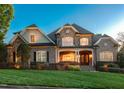 Charming two-story brick and stone home at dusk with warm interior lights at 121 Highclere Ln, Cary, NC 27518