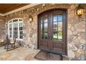Inviting stone-covered porch with rocking chairs and a double-door entryway at 121 Highclere Ln, Cary, NC 27518