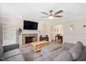 Cozy living room featuring a brick fireplace, ceiling fan and comfortable gray sectional sofa at 202 Lighthouse Way, Cary, NC 27511