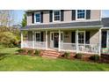 Inviting front porch featuring white railings, brick steps, and a decorative wreath on the front door at 206 Herronwood Dr, Graham, NC 27253