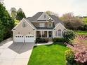 Beautiful two-story home featuring a stone facade, a covered porch, a well-manicured lawn, and a three-car garage at 213 Billingrath Turn Ln, Cary, NC 27519