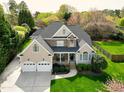 Aerial view of a two-story home with a three-car garage, well-manicured lawn, and mature trees on a sunny day at 213 Billingrath Turn Ln, Cary, NC 27519