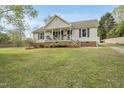 Inviting home with a covered porch, complemented by lush green lawn and mature landscaping at 221 Walkers Way, Willow Springs, NC 27592