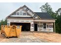 New construction shows a modern home with an attached garage and covered porch being built on a wooded lot at 23 Fetterbush Way, Clayton, NC 27520