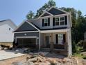 Charming two-story home featuring a brick porch, open garage, and light gray and navy blue siding at 49 Fetterbush Way, Clayton, NC 27520