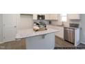 Bright kitchen with white cabinets, stainless steel appliances, tile backsplash, countertop island, and gray flooring at 49 Fetterbush Way, Clayton, NC 27520