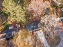 Aerial shot of a single-story home with a dark roof, concrete driveway, and surrounded by trees at 5917 Meadowlark Ln, Raleigh, NC 27610