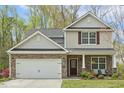 Two story home featuring a stone facade, attached garage, and manicured lawn at 6021 Watsonia Dr, Zebulon, NC 27597
