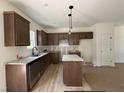 Bright kitchen featuring wood floors, granite counters, brown cabinets, and stainless steel appliances at 61 Fetterbush Way, Clayton, NC 27520