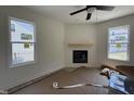 Living room featuring light colored walls, a fireplace, two windows, and a ceiling fan at 61 Fetterbush Way, Clayton, NC 27520