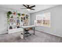 Bright bedroom featuring a large window, neutral carpet, and a modern built-in shelving unit with plants at 6412 Nurture Ave, Raleigh, NC 27616