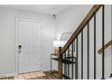 Inviting entryway with a white door, stylish light fixture, and modern staircase with metal railings at 6412 Nurture Ave, Raleigh, NC 27616