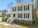Classic two-story home with light yellow siding, black shutters, brick foundation, and landscaped front yard at 7109 River Birch Dr, Raleigh, NC 27613