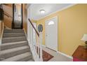 Bright foyer with staircase, neutral carpet, and view of the front door and a decorative rug at 7109 River Birch Dr, Raleigh, NC 27613