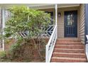 Inviting front porch with brick steps and white railings, framed by a lush green tree at 7212 Rabbit Run, Wake Forest, NC 27587