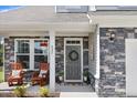 Inviting front porch featuring rocking chairs and stylish stone detailing at 825 Golden Plum Ln, Zebulon, NC 27597