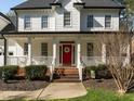 Inviting entrance with a striking red door, brick steps, and a well-maintained front garden at 317 Flatrock Ln, Holly Springs, NC 27540