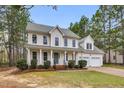 Two-story home with a two-car garage, green lawn and a covered front porch at 384 Rocky Run Ln, Lillington, NC 27546