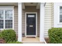 Inviting front entryway with elegant columns, a black door, and manicured shrubs at 4114 Brenmar Ln, Durham, NC 27713