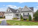 Beautiful home showcasing a manicured lawn, two-car garage, and a welcoming front porch, radiating curb appeal at 8925 Hopkins Knob Ct, Zebulon, NC 27597