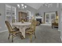 Cozy dining area with chandelier, fireplace view, and natural light from the windows at 11251 Lofty Heights Pl, Raleigh, NC 27614