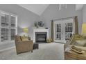 Bright living room with fireplace, vaulted ceilings, and French doors to the outside at 11251 Lofty Heights Pl, Raleigh, NC 27614