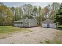 View of the single-story home's exterior, featuring a detached garage and a spacious gravel driveway at 114 Marshay Meadow Rd, Youngsville, NC 27596