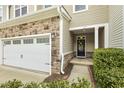 Inviting front entrance featuring a stone facade, a well-maintained lawn, and a black front door at 207 Wildfell Trl, Cary, NC 27513