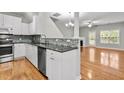 Bright kitchen with white cabinetry, stainless steel appliances, granite countertops, and an adjacent living space at 2100 Thornblade Dr, Raleigh, NC 27604