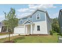 Two-story home with a two-car garage and landscaping, accented by a young tree and green lawn at 2207 Cherry Creek Rd, Haw River, NC 27258