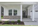 Inviting covered porch with brick accents, columns, and manicured landscaping leading to the front entrance at 3849 Rosebush Dr, Zebulon, NC 27597
