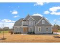 Charming gray two-story home with classic architecture, complemented by a well-kept lawn, on a sunny day at 45 Melody Dr, Youngsville, NC 27596
