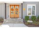 Inviting entryway featuring a beautiful wooden front door with decorative wreaths and stone steps at 45 Melody Dr, Youngsville, NC 27596