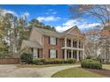 Side view of a brick home with a two story porch, a driveway, and lush landscaping at 5521 Erinvale Ct, Holly Springs, NC 27540