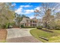 Attractive brick home with a curved driveway lined with trees and well maintained landscaping at 5521 Erinvale Ct, Holly Springs, NC 27540