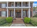 Close-up of home's front entrance showing brick stairs, columns, and manicured bushes at 5521 Erinvale Ct, Holly Springs, NC 27540